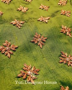 green and gold embroidered fabric with small flowers on the side, closeup shot from above