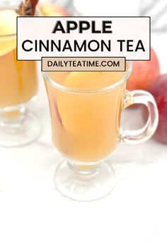 two glasses filled with apple cinnamon tea on top of a white table next to apples