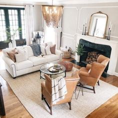 a living room filled with furniture and a fire place under a chandelier in front of a fireplace