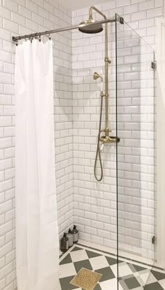 a white tiled bathroom with black and white checkered flooring, shower head, and curtain