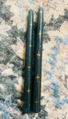 two green candles sitting on top of a carpet covered in stars and snowflakes