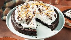 a chocolate cake topped with whipped cream and orange zest on a white platter