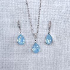 "This beautiful handmade small and delicate crystal teardrop dangle bridal earrings, necklace and bracelet feature ice blue opal pear shaped European crystal fancy stones. The small pear stones measure 10x14mm and are hand set in your choice of plated settings (rhodium (silvertone), yellow or rose gold). The earrings feature cz set french hooks, the necklace features a cz set bail and 18\" 925 sterling silver chain and the bracelet features a bolo type bracelet so fits any size wrist. Really beautiful quality and amazing sparkle perfect for your wedding or special occasion! For pierced ears.  Measurements:  Earrings: 1-1/4\" L x 3/8\" W Necklace: 18\" L Drop: 1\" Bracelet: Adjustable bolo bracelet--will fit any size wrist Available with rhodium plate (silvertone), yellow or rose gold plate Teardrop Blue Jewelry With Sparkling Stones, Teardrop Blue Sparkling Stones Jewelry, Light Blue Crystal Jewelry For Formal Occasions, Blue Briolette Necklace For Wedding, Dainty Blue Drop Jewelry, Blue Teardrop Cubic Zirconia Jewelry Sets, Blue Cubic Zirconia Teardrop Jewelry Sets, Light Blue Drop Jewelry For Gift, Briolette Cubic Zirconia Wedding Jewelry