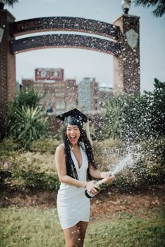 a woman in graduation cap and gown throwing water on her head