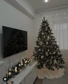 a decorated christmas tree in the corner of a living room with white lights and decorations