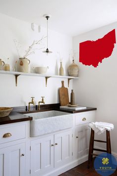 a kitchen with white cabinets and red paint on the wall above the sink is shown