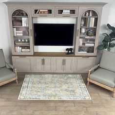 a living room with two chairs and a large tv on the wall above it is an area rug