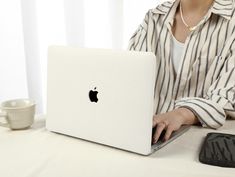 a woman sitting at a table with an apple laptop