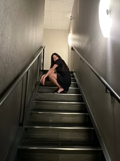 a woman is sitting on the stairs in an empty building with her head down and hands behind her back