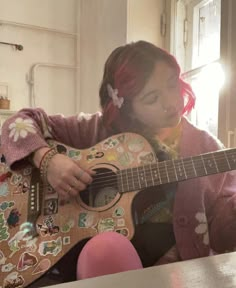 a girl with red hair playing an acoustic guitar