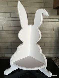 a white cardboard bunny shaped shelf on top of a black counter next to a brick wall