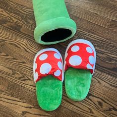 two slippers are laying on the floor next to a green tube and a red mushroom