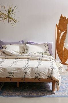 a bed with white sheets and purple pillows in a room next to a large mirror