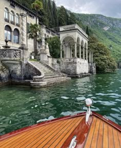 a boat traveling down a river next to a large building with columns on the side