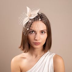 a woman wearing a white veil with a flower on it's head is looking at the camera