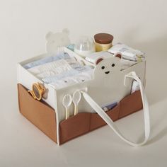 a baby crib with scissors, diapers and other items in it on a white surface