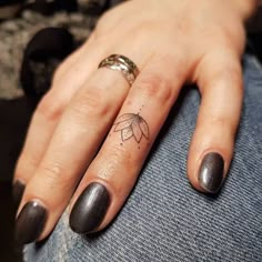 a woman's hand with a small tattoo on her left thumb and ring finger