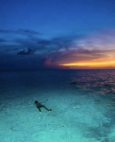 a man swimming in the ocean at sunset