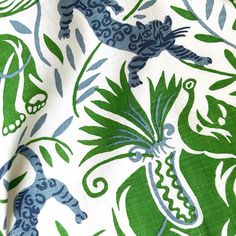 a green and blue animal print fabric with leaves on the bottom, and an animal in the middle