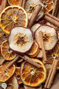 sliced oranges and cinnamon sticks are arranged in a pile on a table with spices