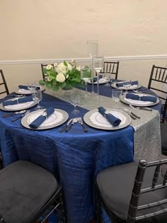 the table is set with blue linens and place settings for four people to sit at