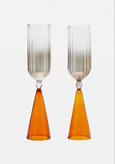 two orange vases sitting next to each other on a white surface with no one around them