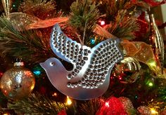 a bird ornament on top of a christmas tree with lights and ornaments around it