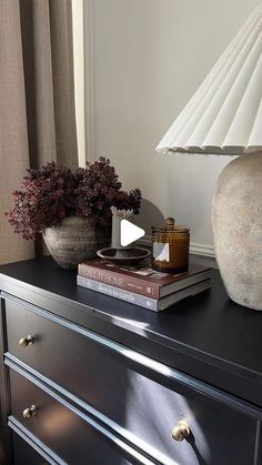 a dresser with two books and a lamp on top