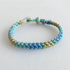 a close up of a beaded bracelet on a white surface with blue, yellow and green beads