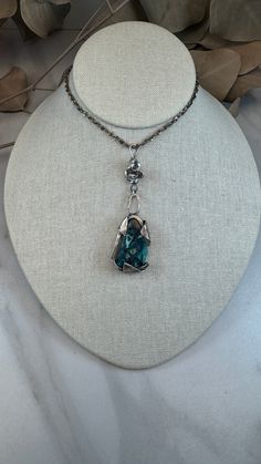 This stunning handcrafted piece highlights the natural beauty of Chrysocolla with native copper. This unique pendant features a live-edge Chrysocolla stone, its vibrant turquoise and teal hues accentuated by rich copper veins, creating a harmonious blend of earthy tones and calming energy. The stone is securely encased in a custom sterling silver setting designed to mimic the organic shapes of nature, making this piece both elegant and bold. Each necklace is meticulously crafted with intention, Live Edge Design, Unique Pendant, Earthy Tones, Organic Shapes, Metal Working, Copper, Pouch, Turquoise, Sterling Silver