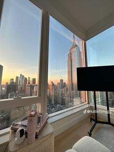 a living room filled with furniture and large windows overlooking the cityscape at sunset