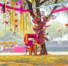 an elaborately decorated tree in the middle of a park with decorations hanging from it's branches