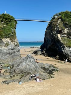 people are sitting on the beach under a bridge