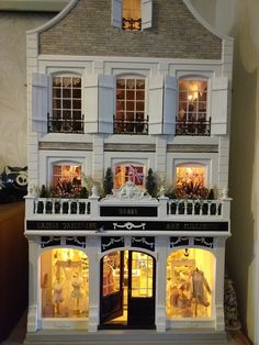 a doll house is lit up with christmas lights and decorations on the front porch,