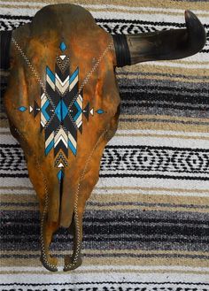 an animal's skull with blue and white designs on it sitting on a striped rug