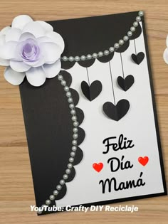 a card with some paper flowers and beads hanging from it's side on a wooden table