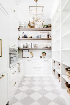 a white kitchen with open shelving and baskets on the countertop, in front of an oven