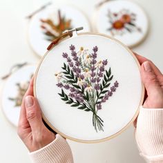 a person holding up a cross - stitch embroidery kit with flowers on it