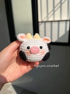 a hand holding a small crocheted pig