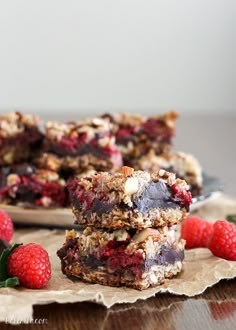 raspberry granola bars stacked on top of each other with fresh raspberries