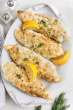 baked fish with lemons and herbs on a white plate