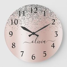 a pink clock with silver glitters on the face and numbers in black lettering that read,'alvia '