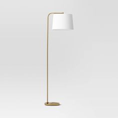 a gold floor lamp with a white shade on the base and a round light fixture