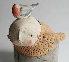 a ceramic bird sitting on top of a piece of pottery