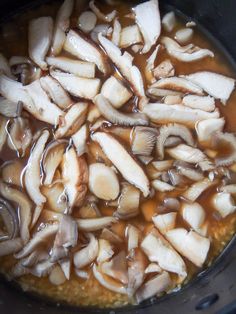 mushrooms are being cooked in a pot with broth and brown liquid on the side