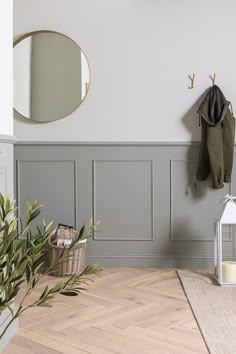 a room with a mirror, coat rack and potted plant on the floor next to it