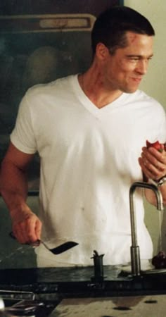 a man standing in front of a sink holding a knife