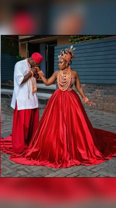 a man and woman dressed in traditional african garb dance together on a brick walkway