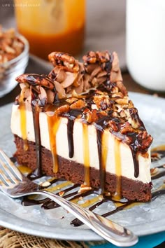 a piece of cake on a plate with chocolate sauce and pecans in the background