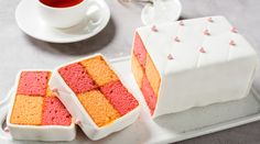 two pieces of cake sitting on top of a white tray next to a cup and saucer